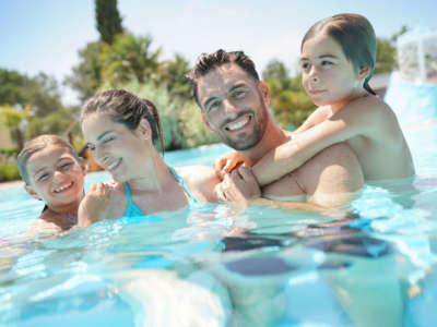 Portrait of happy family at the swimming-pool in summer